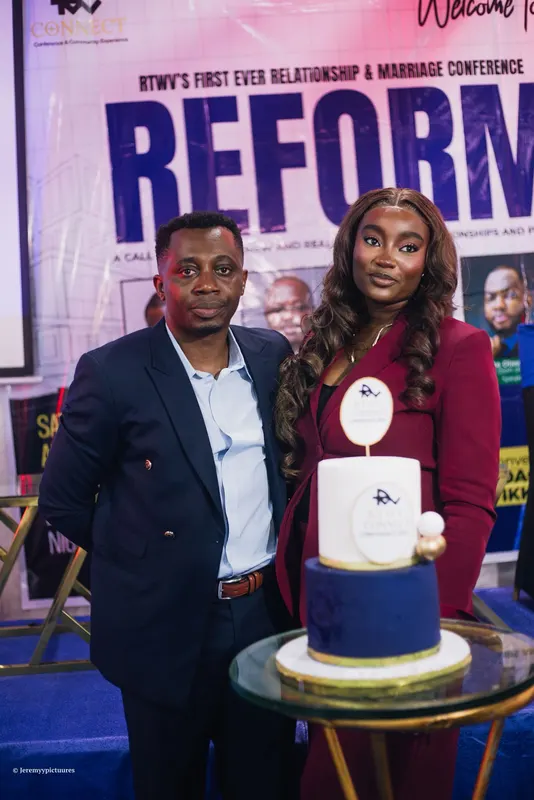 Two people standing beside the RTWV Connect Conference 2026 cake in front of the Reform banner