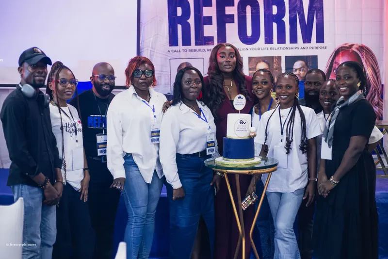 Volunteers and the speaker in a maroon suit gathered around the RTWV Connect cake