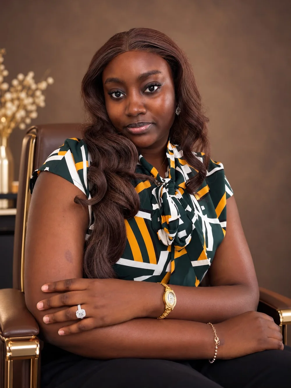 Coach Vikkie seated in a green, gold and white print top, arms folded